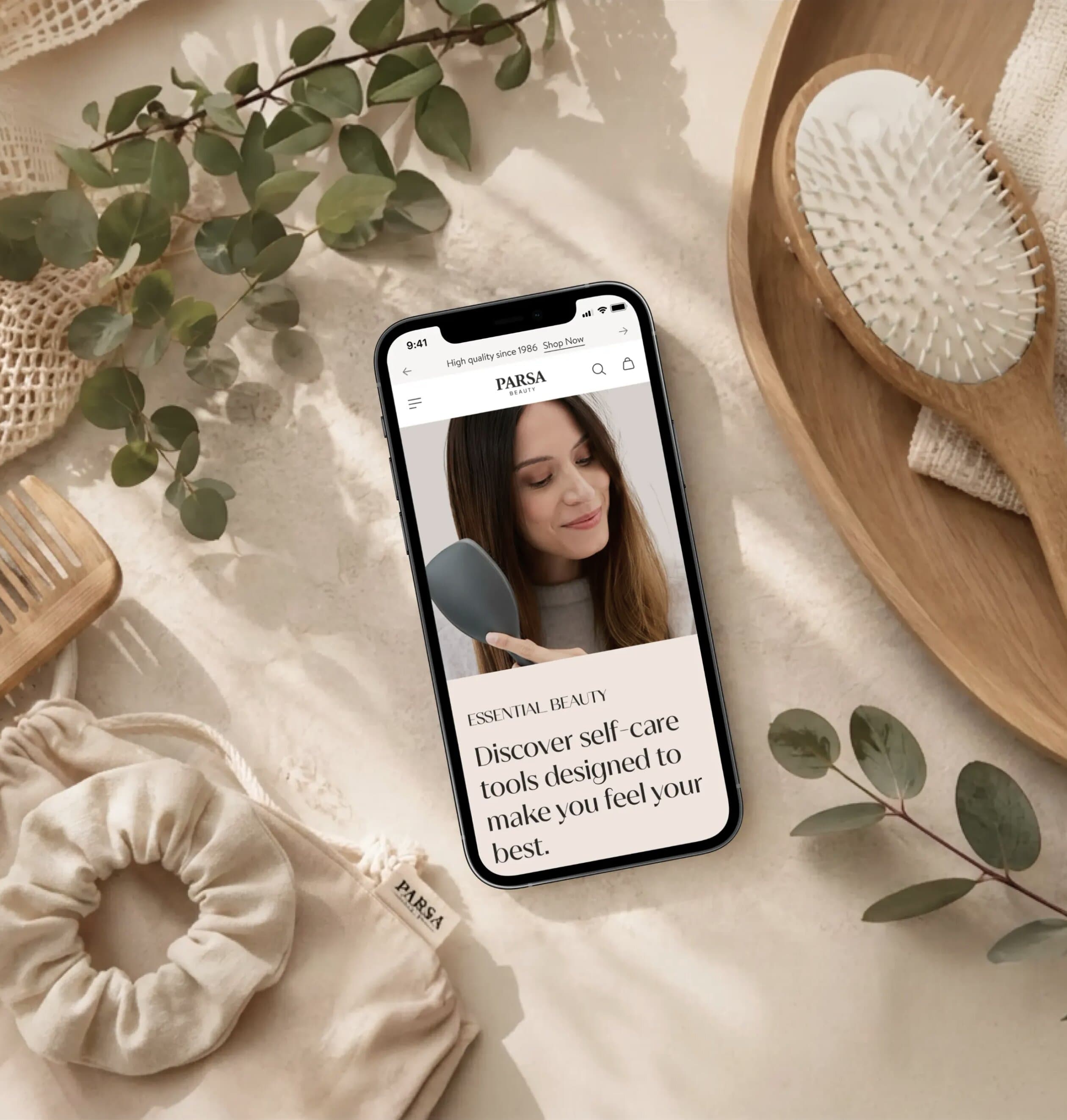 PARSA Beauty Store auf einem Smartphone neben Haarbürsten und grünen Blättern