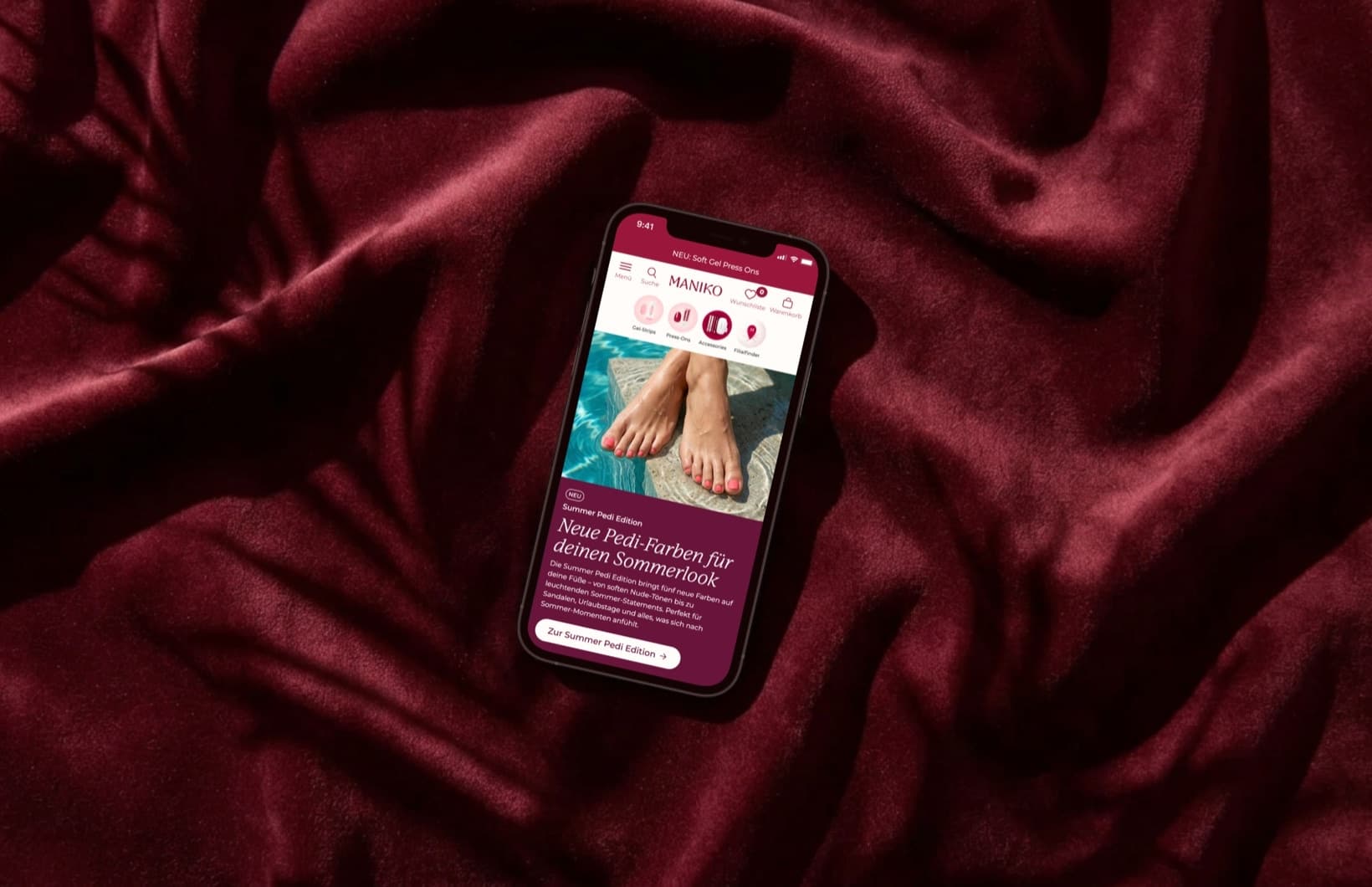 Der Maniko-Nails-Storefront auf einem Smartphone auf dunkelrotem Stoff